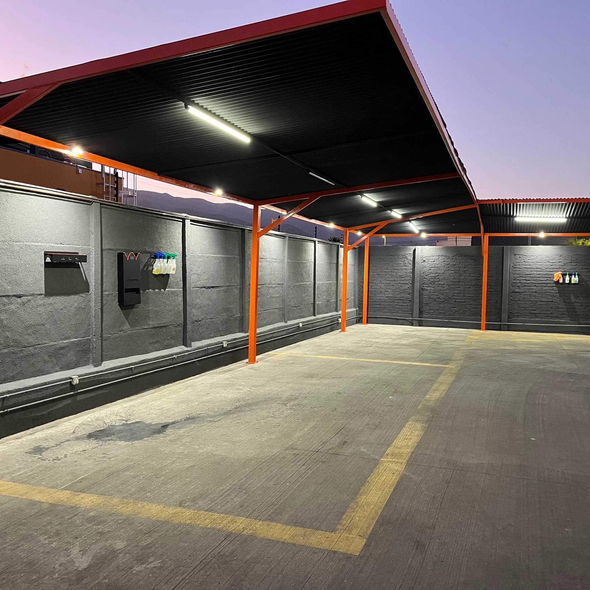 Sucursal techada de Orange Servicentro con estructura naranja, iluminacion y zonas de trabajo marcadas